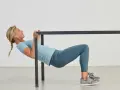 Kvinna utför overhead triceps extension vid en ställning.