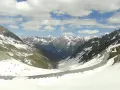 Strada tortuosa sulla Ötztaler Gletscherstraße, tra montagne innevate e cielo azzurro con nuvole bianche.