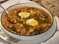 Potaje de garbanzos con bacalao y huevo duro en un cuenco blanco.