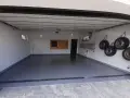 Nowa, lśniąca posadzka w garażu, cztery koła wiszące na ścianie, drabina i tablica narzędziowa.