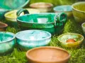 Varietà di ciotole in ceramica smaltata, che ricordano diversi tipi di argilla per modellare, disposte sull'erba.