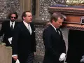 Smutni żałobnicy niosą trumnę. Wśród nich jest mężczyzna, który mógł być synem Erica Claptona.