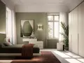 Camera da letto con pareti verdi e un letto accogliente. L'arredamento verde crea un'atmosfera rilassante, con un quadro astratto e un grande armadio bianco.