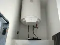 Scaldabagno elettrico bianco con tubi e rubinetto. Potrebbe esserci aria nello scaldabagno elettrico, ma l'immagine non lo mostra.