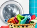 A basket of colorful clothes in front of a washing machine.
