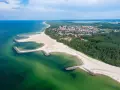 Malownicze plaże w Polsce z kamiennymi falochronami, zielonymi wodami Bałtyku i nadmorskim miasteczkiem w tle.