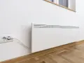 Termoconvettori bianchi montati a parete, uno collegato a una presa elettrica, pronti a riscaldare l'ambiente.