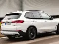 Białe BMW X5 M50d pędzi po autostradzie, zostawiając za sobą rozmyte tło.