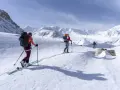 Trois skieurs s'aventurent dans un paysage montagneux enneigé. Une photo ski montagne qui capture l'immensité et la beauté de la nature.