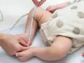 Dziecko w body w kropki, mierzone centymetrem. Sprawdzanie, jaki to rozmiar dla malucha do 3 miesięcy.