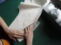 Mains travaillant sur un patron de couture, ajustant un tissu pour une poche raglan, à côté d'une machine à coudre Singer.