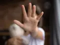 Main d'enfant tendue en signe d'arrêt, tenant une peluche.