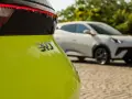 Jasnozielony samochód elektryczny BYD z napisem "310" na klapie bagażnika, w tle biały samochód.