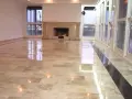 Pavimento in marmo beige con finitura a specchio, che riflette le luci e le finestre. Un lavoro di lucidatura perfetto per un ambiente elegante.