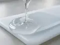 Clear resin pours onto a white acrylic surface, showing how does resin stick to acrylic.