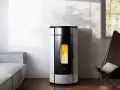 Estufa de leña canalizable moderna con llamas encendidas, junto a un sofá gris y una silla de cuero.