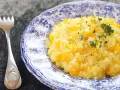 Pyszny, kremowy ryż do risotto z kawałkami dyni, posypany świeżym tymiankiem i pieprzem. Obok leży ozdobny widelec.