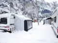 Zimowe krajobrazy w Polsce zachęcają do odkrywania kempingi całoroczne. Przyczepy kempingowe i kampery pokryte śniegiem w górskiej scenerii.