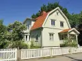 Ljusgrönt trähus med tegeltak och vit staket. En vacker trädgård med blommande buskar. Planerar att byta fasad för att fräscha upp huset.