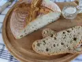 Chleb nocny na zakwasie, pokrojony na desce, z widocznym puszystym wnętrzem i chrupiącą skórką. Obok mała miseczka z solą.
