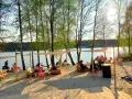 Relaks na piaszczystej plaży nad jeziorem. Ludzie odpoczywają w cieniu namiotów, tworząc przytulne pola namiotowe nad jeziorem.