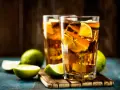Dwa orzeźwiające drinki: Long Island Iced Tea czy Tokyo Tea, z lodem i limonką, na drewnianej desce.