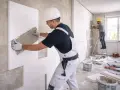 Operai al lavoro per i lavori di coibentazione, applicano pannelli isolanti su una parete interna.