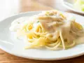 Pyszny makaron spaghetti polany kremowym sosem serowym, gotowy do podania.
