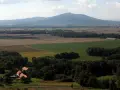 Widok na górzystą okolicę obok Wrocławia z polami, lasami i kilkoma domami.