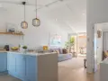 Cocina y sala de estar luminosas, perfectas para decorar casa playa poco presupuesto. Muebles claros, plantas y detalles náuticos crean un ambiente fresco.
