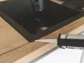 Pistolet z silikonem aplikuje uszczelnienie wokół zlewu, pokazując, jak polożyć silikon na blacie kuchennym.