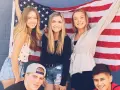 Freunde feiern ihr High School Jahr in den USA vor einer amerikanischen Flagge.