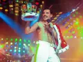 Freddie Mercury, król sceny, w koronie i z mikrofonem, na tle kolorowych świateł.