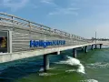Hol dir die besten heiligenhafen tipps! Die Seebrücke mit dem Schriftzug "Heiligenhafen" ragt ins grüne Meer.