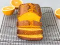 Un delicioso bizcocho de naranja, recién horneado y cortado en rebanadas, reposa sobre una rejilla.