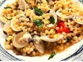 Piatto di fregola con vongole, pomodorini e basilico fresco. Un classico sardo che profuma di mare.