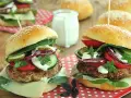 Dwa soczyste burgery wołowe z dodatkami na drewnianym tle.