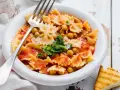 Farfalle-Pasta mit Kichererbsen in Tomatensauce, garniert mit Petersilie und Parmesan. Ein einfaches ceci rezept, perfekt für ein schnelles Mittagessen.