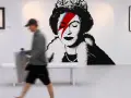 W galerii sztuki widzimy słynne dzieła Banksy'ego: portret królowej z błyskawicą na oku, nawiązującą do Davida Bowiego, oraz inne prace.