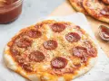 Pyszna pizza z tortilli na patelni, z serem i pepperoni, obok sos w miseczce.