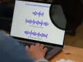 Osoba pracuje przy laptopie, na ekranie widoczne są wykresy fal dźwiękowych, co może być związane z tworzeniem adlibów.