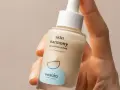 Dłoń trzyma buteleczkę serum Resibo Skin Harmony. Składnik alantoina dba o ukojenie skóry.