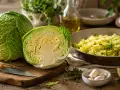 Cavolo cappuccio intero e tagliato a metà, con un contorno di cavolo cappuccio saltato in padella, aglio, limone e erbe aromatiche.