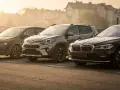 Trzy samochody: ciemny Volkswagen, zielony Renault i czarny BMW, zaparkowane na placu. Wszystkie bez prawa rejestracji.