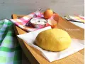 Impasto giallo pronto per essere lavorato, con uova e farina a lato. La pasta frolla senza burro è perfetta per dolci leggeri.