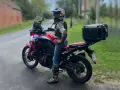 Motocyklistka w kasku i z kufrem na bagażniku gotowa na wyprawę po Kaszubach.