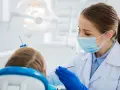 Dentystka bada uśmiech dziecka, by wykluczyć zapalenie dziąseł.