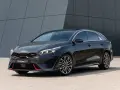 Stylowy, ciemnoszary Kia Proceed GT z czerwonymi akcentami i sportowymi felgami, zaparkowany przed nowoczesnym budynkiem.