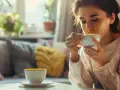 Kobieta pije ciepły napój, szukając ulgi co na jelitówkę.
