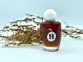 Frasco de aceite de hiperico con tapa blanca, junto a ramas secas.